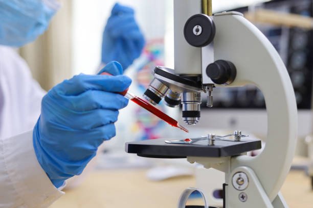 Technician analysing a blood sample under a microscope